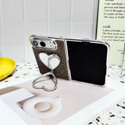 Open iPhone Duo in the black Crystal Heart Duo case resting on a book with heart-shaped stand extended