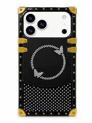 A black protective phone case with gold-tone corner bumpers and straps, featuring a rhinestone-embellished circular arrow design and a rhinestone polka-dot pattern on a white background.