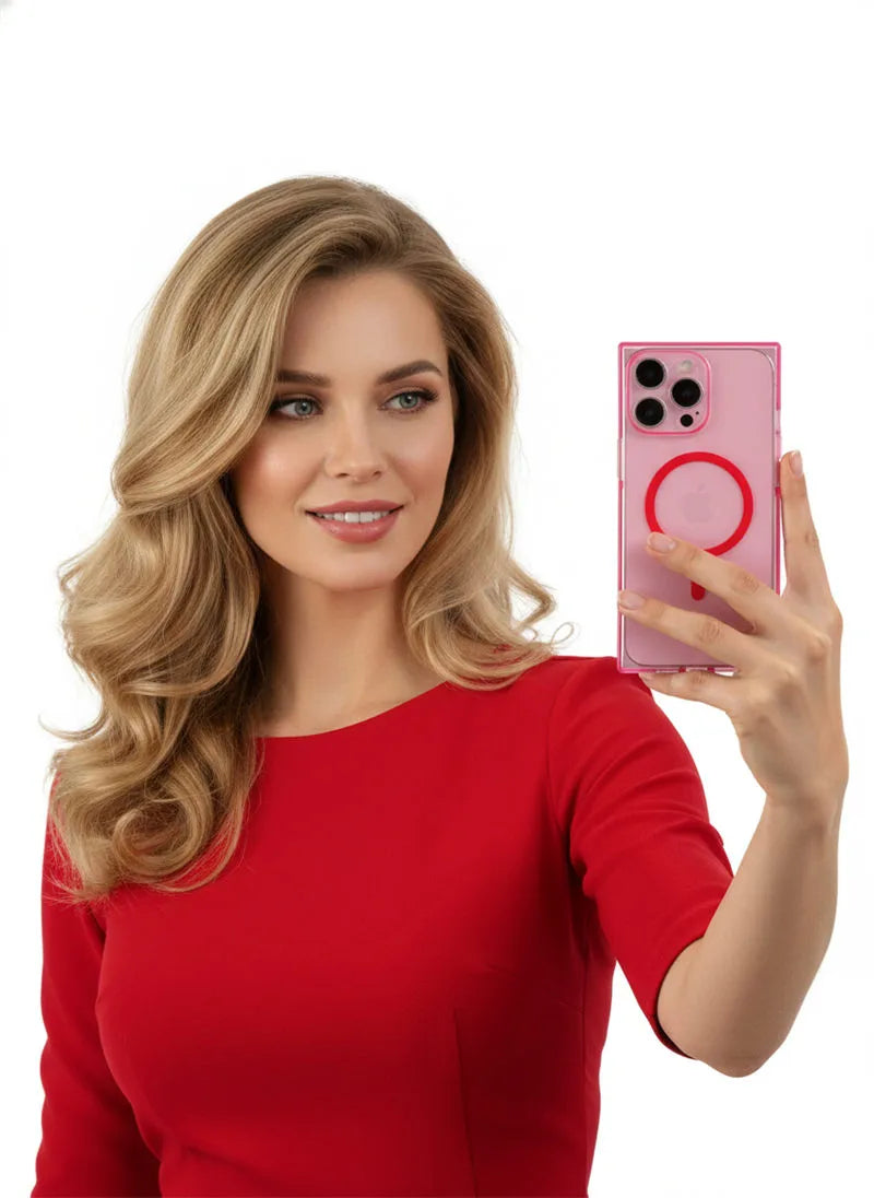 A woman with blonde hair wearing a red top takes a selfie with a pink smartphone that has a circular MagSafe ring on the back, set against a solid white background.
