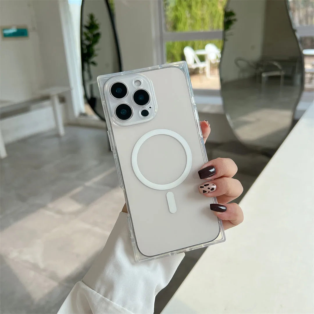 A hand holding a clear MagSafe-compatible phone case with a white magnetic ring, fitted on a light-colored smartphone, set against a bright, modern indoor background.