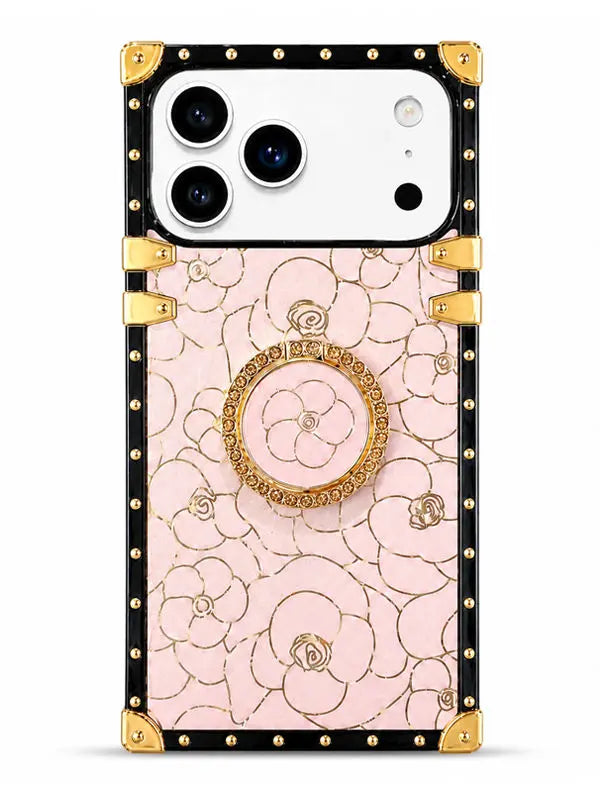A luxury-style phone case featuring a light pink floral pattern with gold outlines, a central gold rose, and a built-in circular gold stand. The case has a black border with gold studs and corner protectors, shown on a white smartphone against a clean white background.