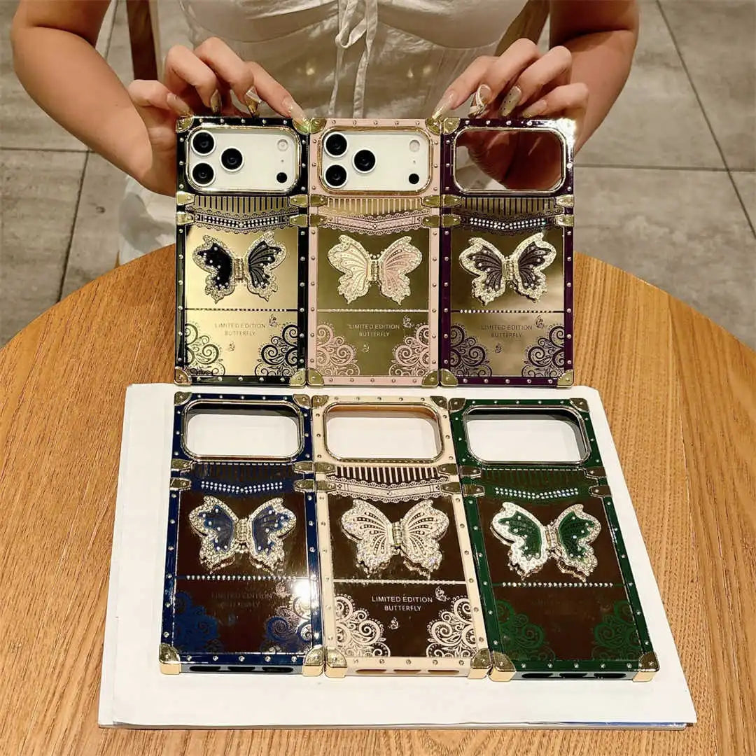Six decorative smartphone cases with large camera cutouts are displayed on a table. A person's hands are visible holding two of the cases at the top.