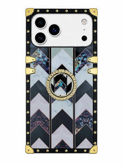 A luxury-style phone case with a black border, gold-tone studs and corner protectors, and a central chevron pattern featuring black, white, and blue-gray marble textures. A circular gold ring with a central 'W' logo is positioned on the back.