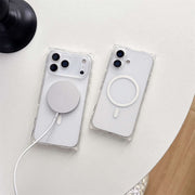 Two clear phone cases with magnetic charging ports on a light surface.