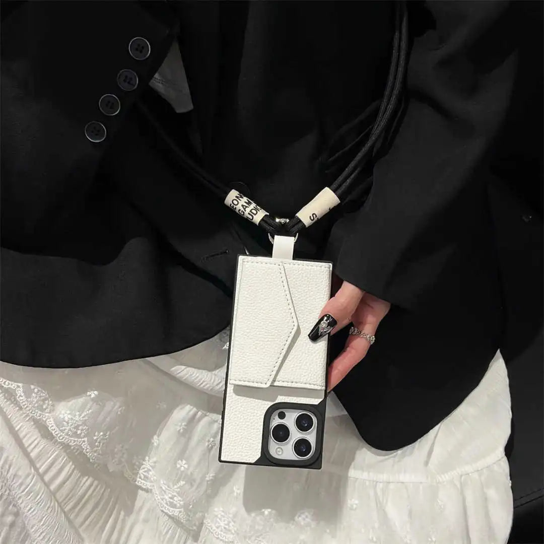 Person holding a white phone case with a strap, wearing a black outfit.