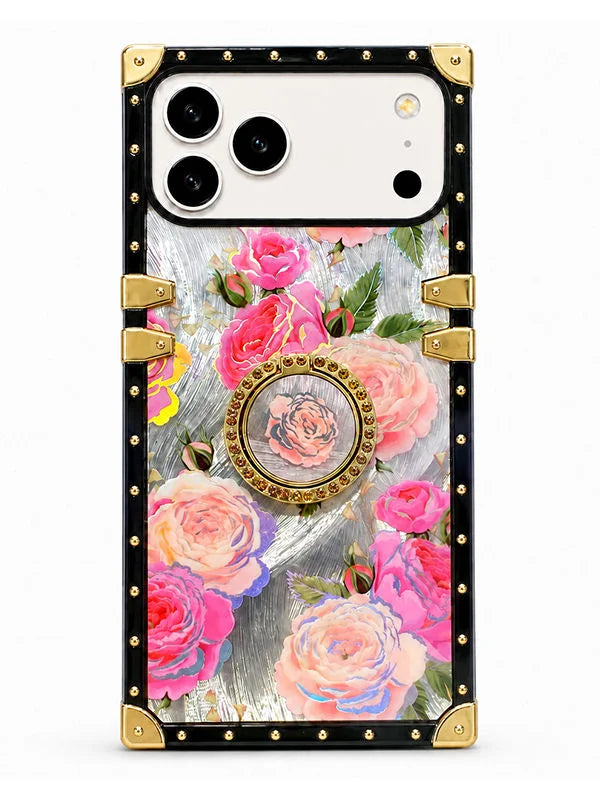 A protective phone case with a luxury design, featuring a black border with gold-tone rivets and corner guards, a central floral print of pink and peach roses, and a circular rose medallion on a light gray textured background.