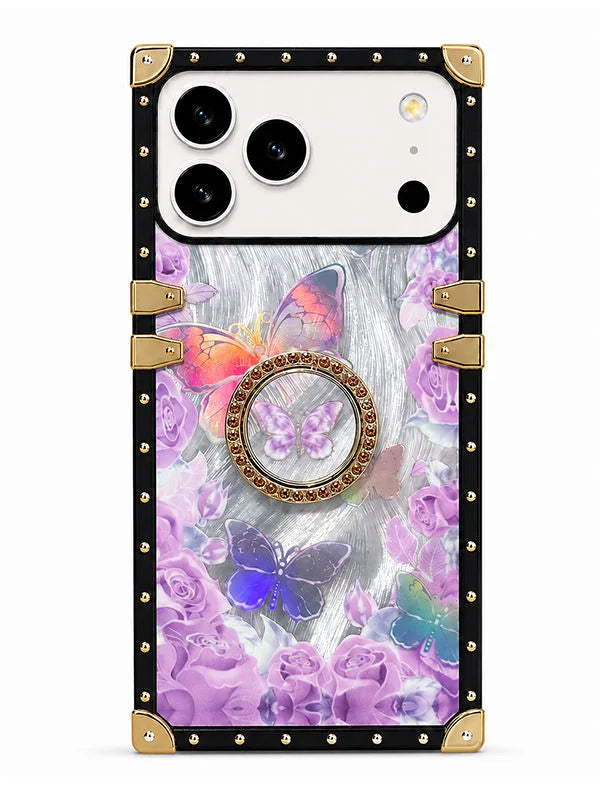 A protective phone case with a black border, gold-tone metal corner guards and latches, and a back panel decorated with purple roses and colorful butterflies on a gray textured background.