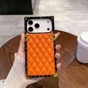 Orange quilted phone case with gold accents held by a hand on a wooden table.