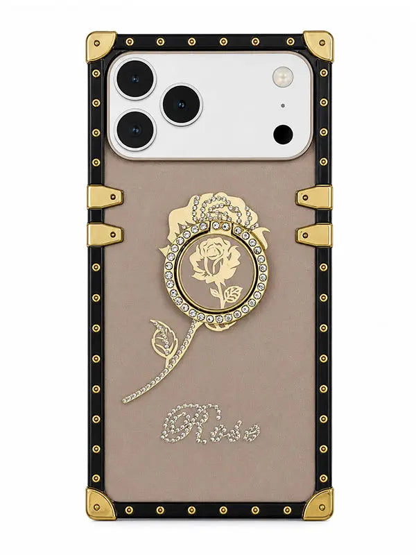 A luxury-style phone case featuring a beige center panel with a gold rose medallion, rhinestone script reading 'Rose', and a black border with gold corner protectors and rivets.
