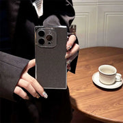 Person holding a smartphone with a reflective case in a casual setting