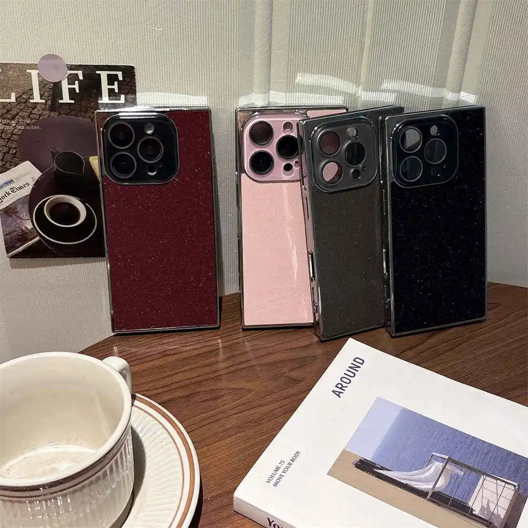 Four phone cases in different colors on a table with a mug and book.