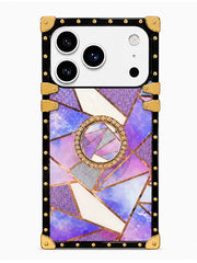 A protective phone case with a black border, gold-tone rivets, corner guards, and a central circular crystal-like motif over a purple, pink, and blue mosaic pattern.