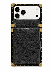 A black textured leather phone case with gold-tone metal corner protectors and rivet details, shown on a white smartphone against a plain white background.