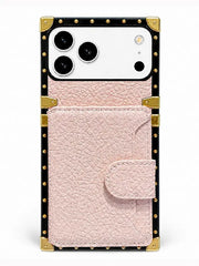 A luxury-style phone case with a light pink textured leather front pocket, a black border, gold-tone metal studs, and corner protectors, shown on a white phone against a clean white background.