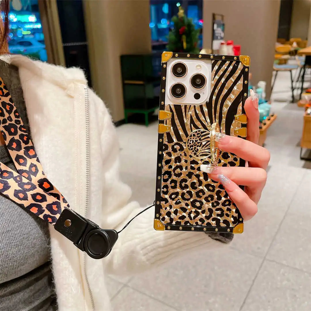 Person holding a phone case with zebra and leopard print design in an indoor setting.