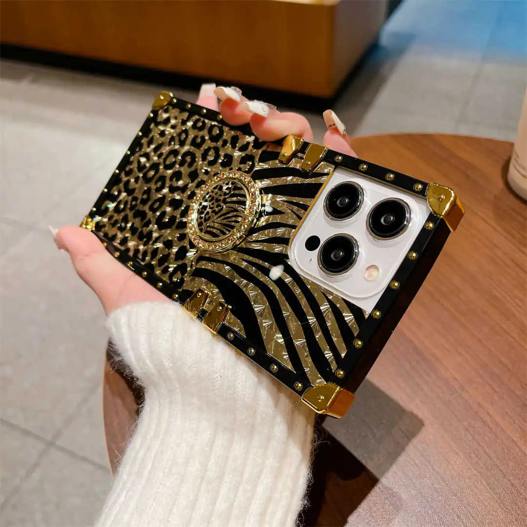 Phone case with leopard print and gold accents held by a person wearing a white sweater.