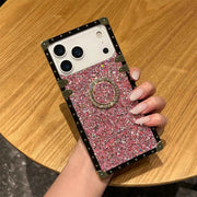 Phone case with pink glittery design and ring holder held by a hand on a wooden surface