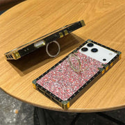 Phone case with glittery design and ring holder on a wooden surface