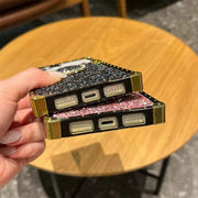 Hand holding a glittery phone case on a wooden table