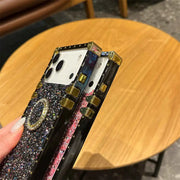 Phone case with glittery design held by a hand on a wooden table