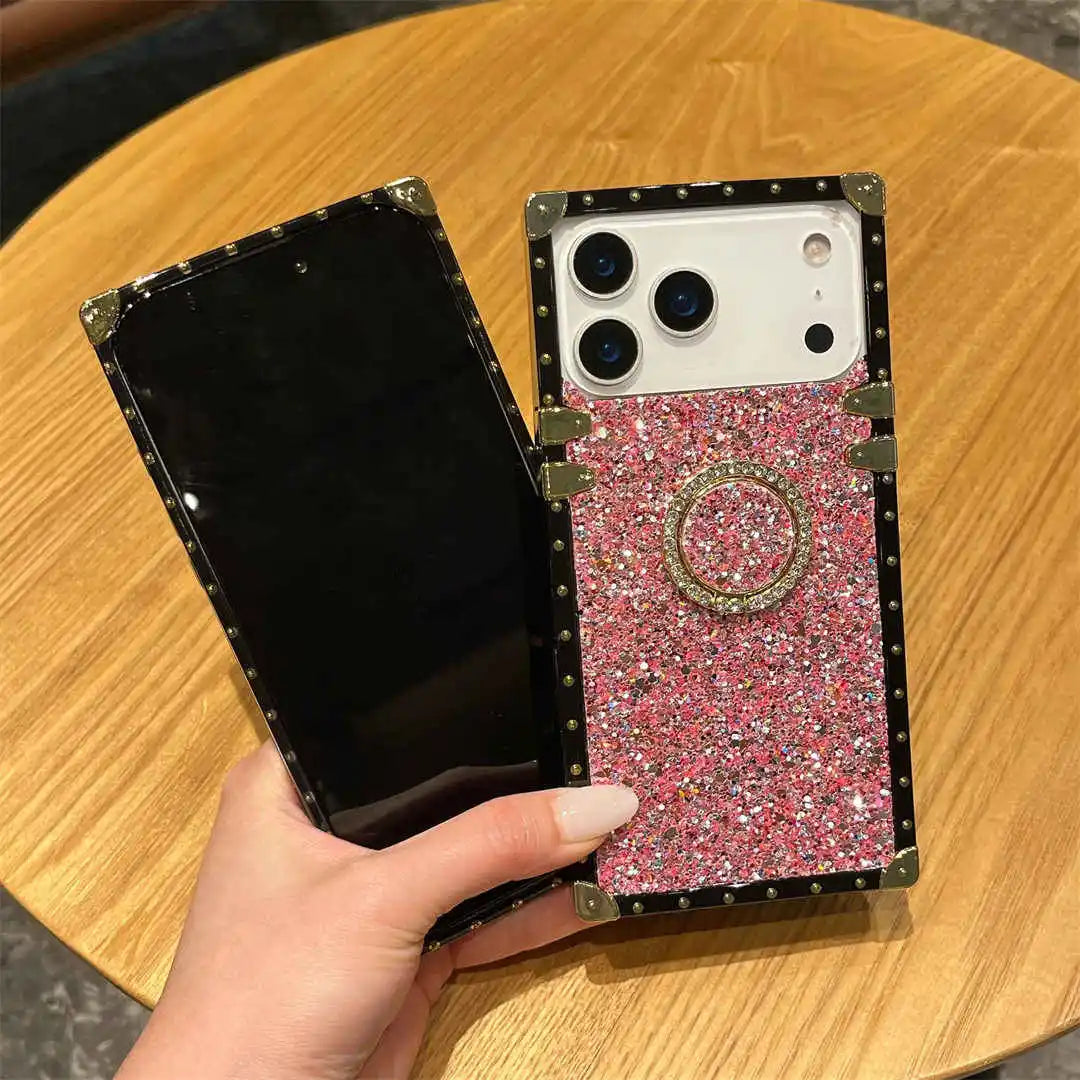 Phone case with pink glittery design held by a hand on a wooden table