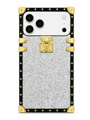 A luxury-style phone case designed for a triple-camera smartphone, featuring a silver glitter center panel, a black border, and gold-tone hardware accents including corner protectors, studs, and a central clasp.