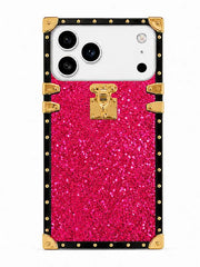 A protective phone case designed with a bright pink glitter center panel and a black border decorated with gold studs, corner bumpers, and a central gold clasp, shown on a white phone against a plain white background.