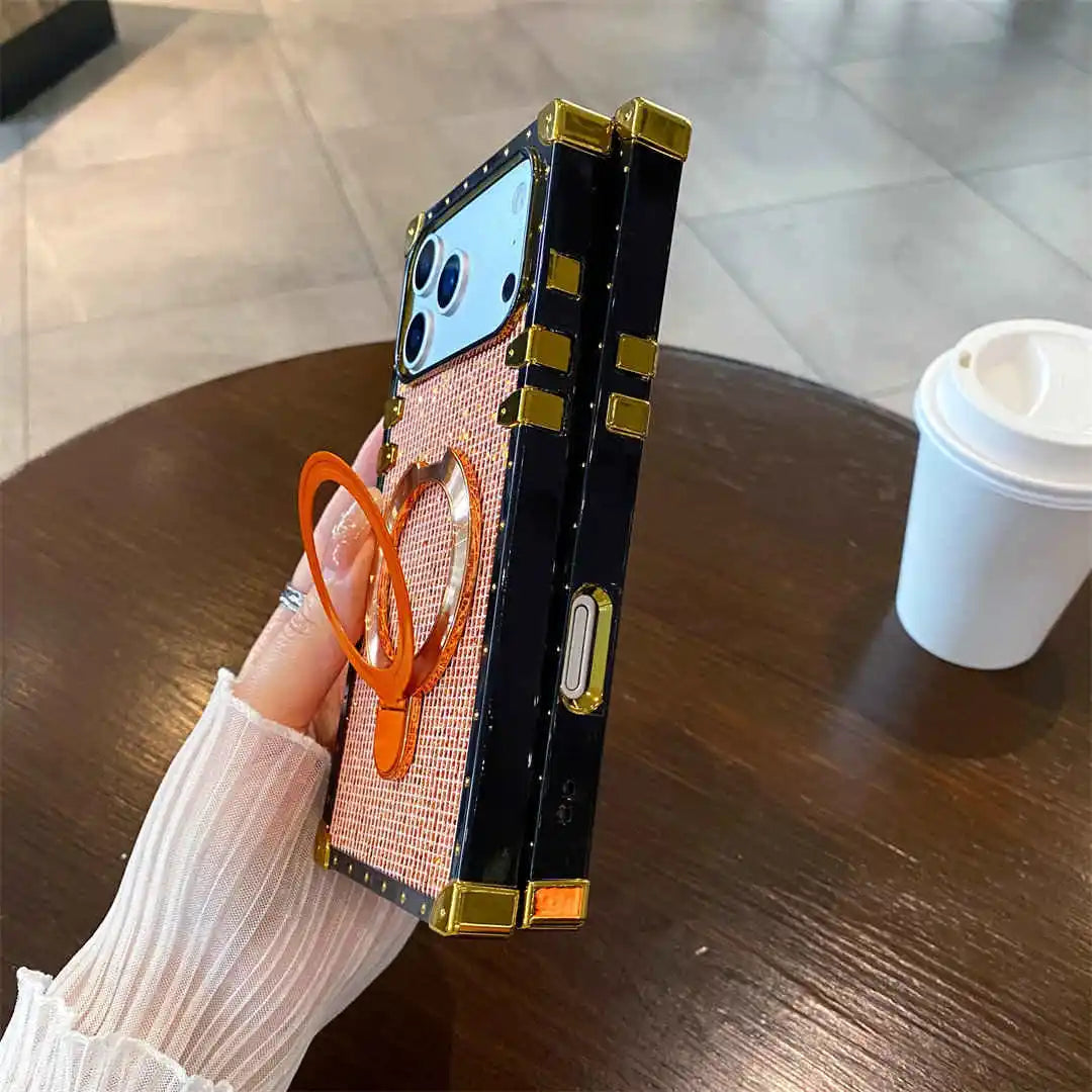 Person holding a phone with a decorative case on a wooden table with a coffee cup in the background.