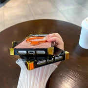 Hand holding a MODA glitter phone case on a wooden table