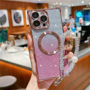 Pink glittery phone case with ring holder and chain held by a hand in a blurred restaurant setting