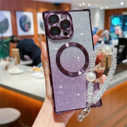 Phone case with glittery design and pearl strap held by a person in an indoor setting.