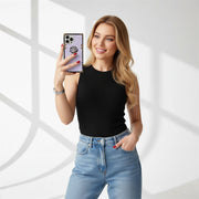 Woman taking a selfie with a phone, wearing a black top and blue jeans, on a white background