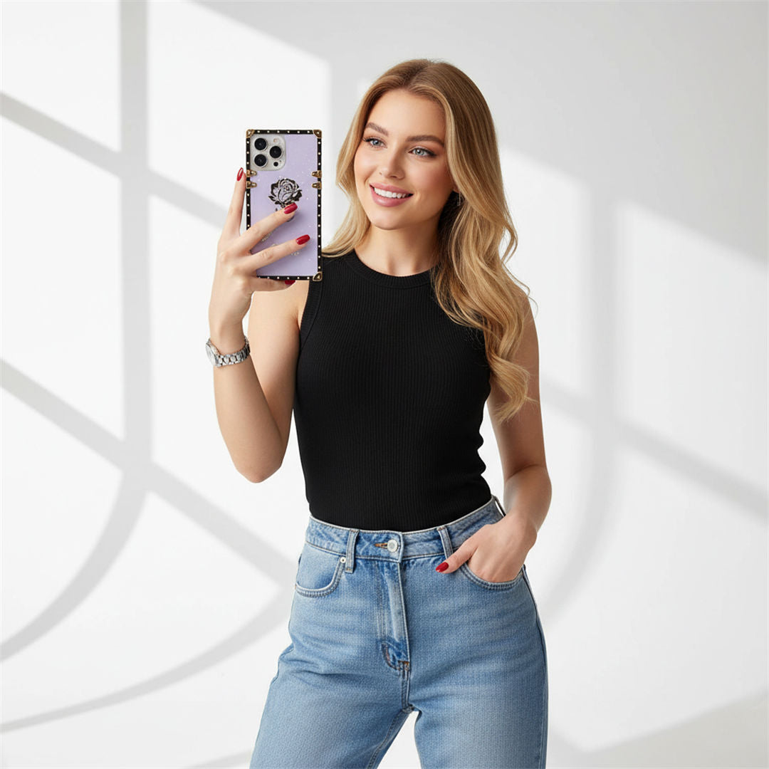 Woman taking a selfie with a phone, wearing a black top and blue jeans, on a white background