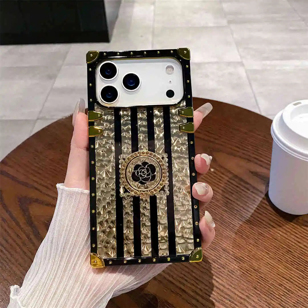 Phone case with decorative design held by a hand on a wooden table.