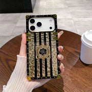Phone case with decorative design held by a hand on a wooden table.