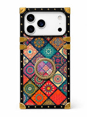 A protective phone case with a colorful bohemian mandala patchwork design, featuring a central circular grip ring and a black border with gold-tone metal studs and corner protectors.