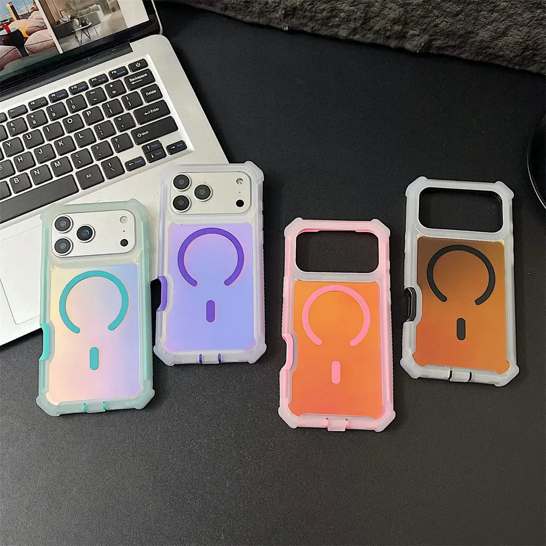 Four protective phone cases with a built-in MagSafe ring are displayed on a dark desk next to a laptop. The cases feature different pastel and gradient color combinations: mint green, lavender, pink, and orange, each with a matching colored ring.