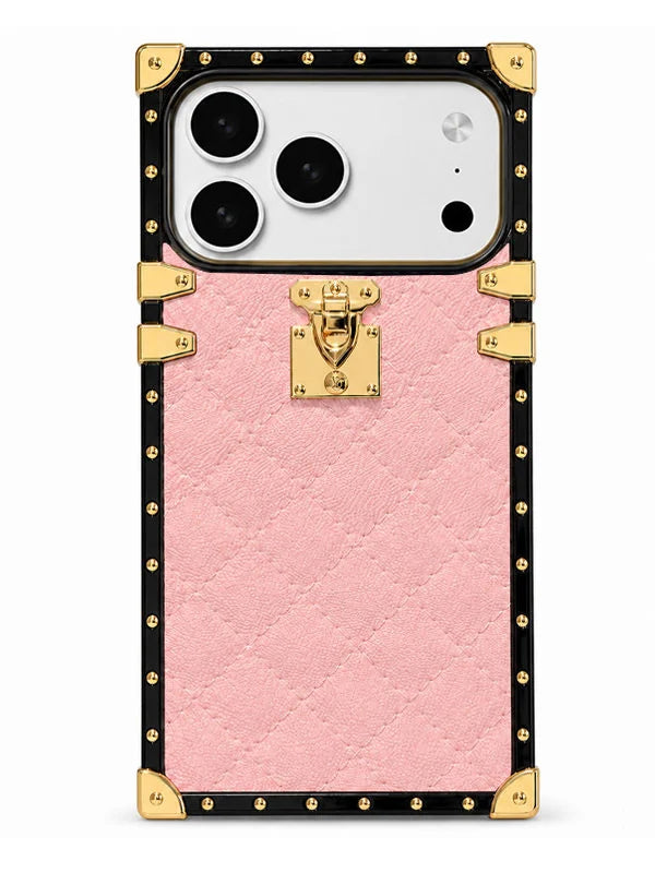 A pink textured phone case designed to look like a luxury trunk, featuring a black border with gold-tone studs, corner protectors, and a central gold clasp lock, shown on a white smartphone.