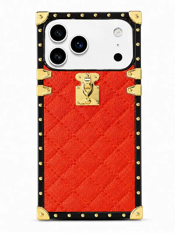 A red textured phone case designed to look like a luxury trunk, featuring a black border, gold-tone studs, corner protectors, and a central gold clasp, shown on a white smartphone.