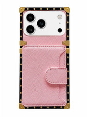 A pink textured faux leather phone case with a snap-button flap and a built-in card pocket, featuring gold-tone metal corner protectors and a black border with gold studs, shown on a white background.