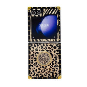 A luxury flip phone case with a black and beige leopard print design, gold-tone studs, and a central circular zebra print medallion, shown on a white background.