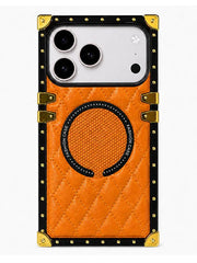 An orange quilted phone case with a black and gold metal-train style border, gold corner protectors, and a circular magnetic ring on the back, shown on a white background.