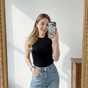 Woman taking a mirror selfie wearing a black top and blue jeans, holding a phone with a floral case.