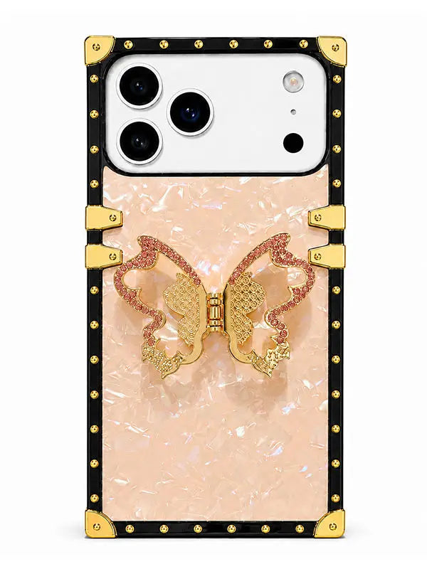 A luxury-style phone case featuring a pale pink marbled center, a gold and pink butterfly embellishment, and a black border with gold rivets and corner protectors, shown on a white smartphone.