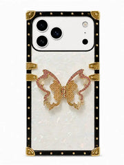 A luxury phone case featuring a white iridescent mother-of-pearl back, a black studded border with gold corner accents, and a central gold and pink rhinestone butterfly embellishment.