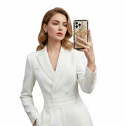 Woman in a white suit holding a phone with a decorative case against a white background