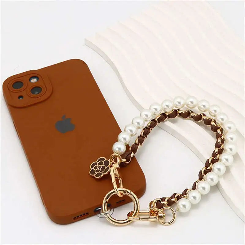 Brown phone case with a pearl and gold chain holder on a white surface