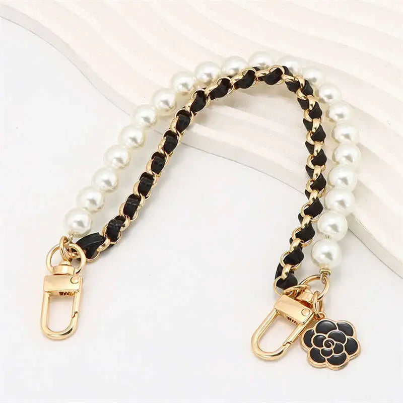Pearl and black chain strap with gold clasp and flower charm on a white background