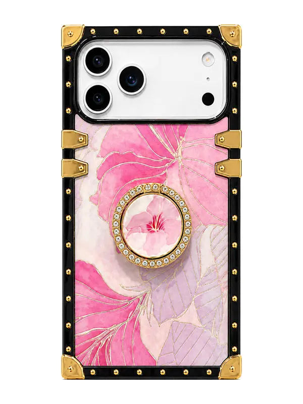A protective phone case featuring a pink and lavender floral print, a central circular crystal-embellished grip ring, and a black border with gold-tone metal studs and corner protectors.