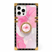 A protective phone case with a pink hibiscus floral print, featuring a black border with gold rivets and corner protectors, a gold-trimmed circular ring, and a central pink flower accent.